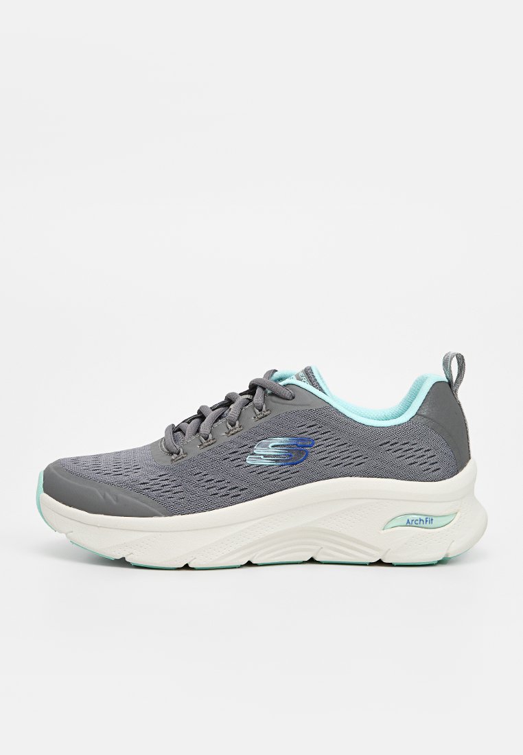 Zapatilla deportiva gris con parte superior de malla, acentos en azul claro, cierre de cordones y suela blanca gruesa etiquetada como "Arch Fit". Presenta un logotipo en el costado.
