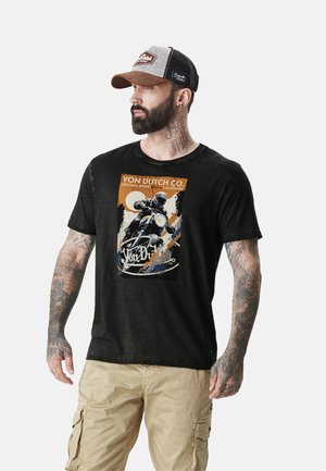T-shirt noir avec un graphique de moto vintage en orange, bleu et blanc. Manches courtes, col rond et coupe décontractée visibles.
