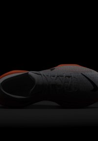 Szürke és narancs Nike sportcipő, fűzővel, fekete háttér előtt, felülnézetből ábrázolva.