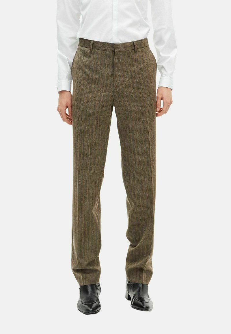 Bruine gestreepte broek in een slim fit, met een vlakke voorkant en ceintuurlussen. Gepaard met zwarte schoenen voor contrast.