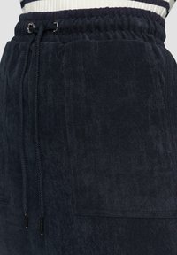 Marineblaue Cord-Jogginghosen mit einem elastischen Bund, Kordelzugverschluss und einer Oberflächentextur mit feinen vertikalen Streifen sowie zwei seitlichen Taschen.