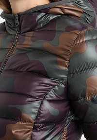 Polstret jakke med hætte i camouflage mønster, der indeholder nuancer af grøn, brun og lilla. Glat tekstur med quiltede sektioner.