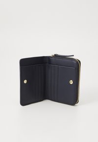Portefeuille en cuir marine avec une fermeture éclair, comportant six emplacements pour cartes et un bouton-pression doré. Texture lisse et design minimaliste.