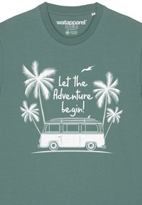 Tijsgroene t-shirt met witte grafische ontwerpen van een vintage bus met surfplank, omringd door palmbomen en tekst: "Laat het avontuur beginnen!"
