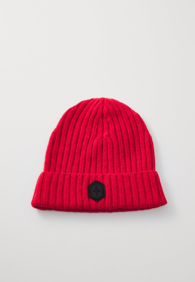 Red knitted beanie with ribbed texture and a folded cuff. Features a black hexagonal patch on the front.