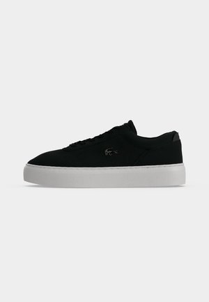 Μαύρο χαμηλό sneaker με λευκή πλατφόρμα στη σόλα και μικρό λογότυπο κροκοδείλου στη πλευρά, εμφανιζόμενο από την εξωτερική πλευρά.