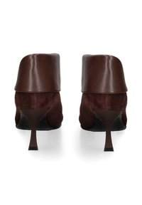 Bruine leren en suedene hakken met een gebogen ontwerp, puntige neus en een slanke hak. Gladde textuur met een subtiele glans.