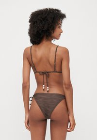Brown bikini with textured fabric. Features slim straps and a tie-back closure. Notable accents include beads on the straps.