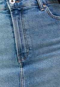 Světle modrá džínová sukně s přiléhavým střihem. Obsahuje zlaté prošívání, přední kapsu a kovové zapínání na knoflík.