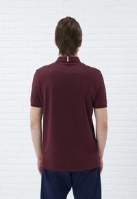 Burgundi värvi polo särk ribaga krae ja seljal triibulise aktsendiga. Kangas näeb välja pehme ja klassikalise lõikega.