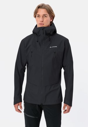 Veste noire imperméable avec un col haut, poches zippées à l'avant, capuche ajustable et logo sur la poitrine gauche. Texture lisse et mate.