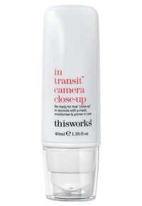 Bouteille cylindrique blanche avec un distributeur, comportant du texte noir et rouge. Nom du produit : "in transit camera close-up," taille indiquée de 40 ml.