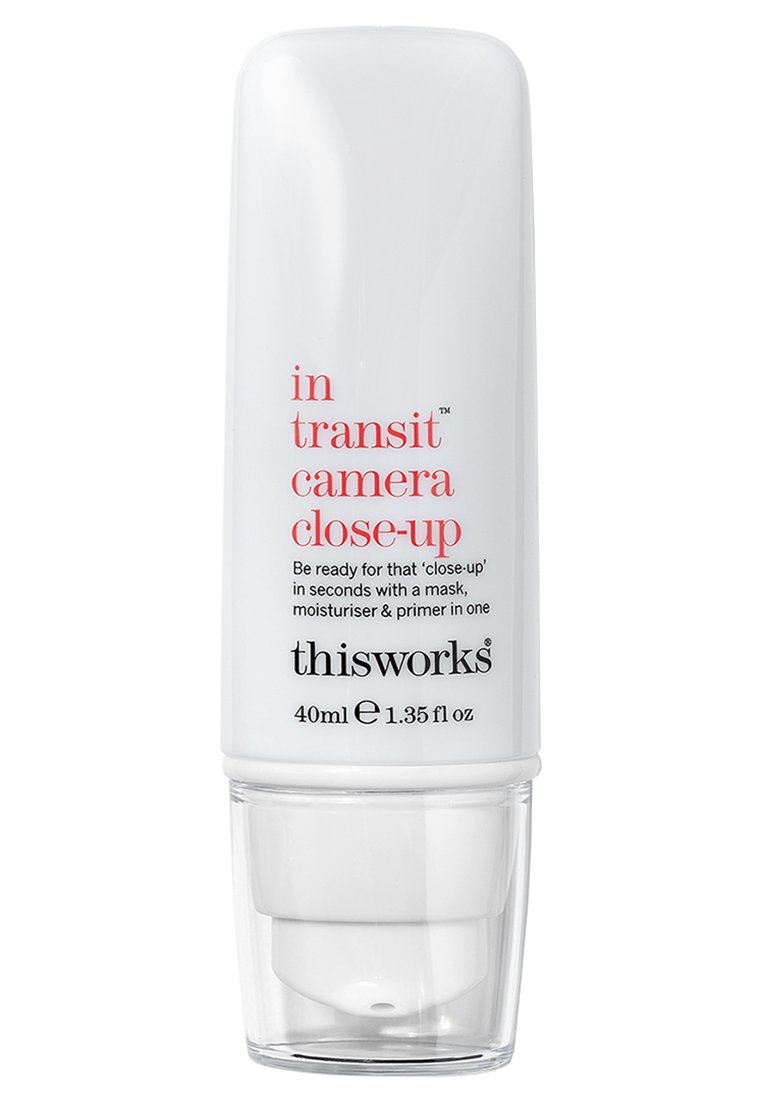 Bouteille cylindrique blanche avec un distributeur, comportant du texte noir et rouge. Nom du produit : "in transit camera close-up," taille indiquée de 40 ml.