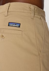 Patagonia helebeežide lähedalt, millel on tagaküljel nööbitav tasku ja nähtav logomärk inimese vöökohal ja puusal.