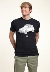 Svart t-shirt med en vit linjeteckning av en klassisk bil på framsidan, rundad hals, korta ärmar och slät tygkvalitet.