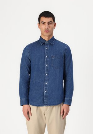 Camicia di jeans blu scuro con colletto button-down, taschino frontale e maniche lunghe. Presenta un logo discreto sulla tasca del petto.