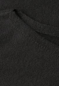 Tessuto nero con una superficie morbida e testurizzata, caratterizzato da un'area leggermente stropicciata. Il materiale sembra elastico e resistente.