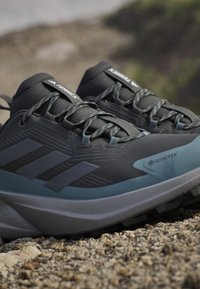 GORE-TEX Trail-Schuhe in Dunkelgrau mit hellgrauen Akzenten. Merkmale sind ein strukturiertes Obermaterial, ein gepolsterter Schaft und eine robuste Gummisohle für besseren Grip.