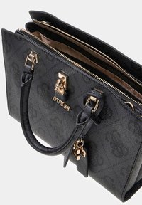 Zwart gestructureerde handtas met goudkleurige hardware, dubbele handgrepen en ritssluitingen. Voorzien van een merklogo en een afneembare hanger.