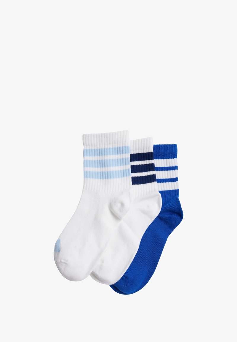 Tres pares de calcetines de algodón: uno blanco con rayas azul claro, uno blanco con rayas azul oscuro y uno azul sólido. Largo hasta la pantorrilla.
