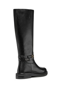 Bota alta de piel negra con textura suave, que presenta una correa decorativa y detalle en hardware dorado. Suela plana y silueta elegante.