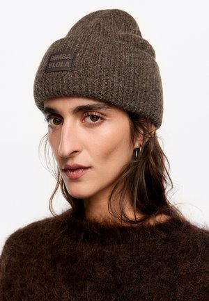 Brązowa czapka dzianinowa z prążkowaną fakturą i wyraźną naszywką marki, stylizowana z podwiniętym mankietem. Miękki materiał, casualowy design.
