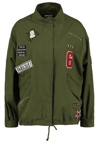 Oliwkowa kurtka z wysokim kołnierzem, zdobiona wieloma naszywkami, haftowanymi detalami i kieszeniami z przodu. Sznurek w dolnej części.