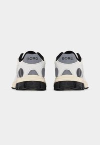 Paire de chaussures de sport blanches et grises avec semelles noires, vues de dos, présentant le nom de la marque "BORG" sur le talon.