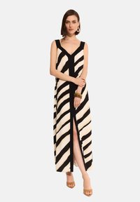 Długa sukienka z czarno-kremowymi ukośnymi paskami, dekoltem w kształcie litery V oraz rozporkiem z przodu. Wykonana z gładkiego materiału, dopełniona dodatkami.