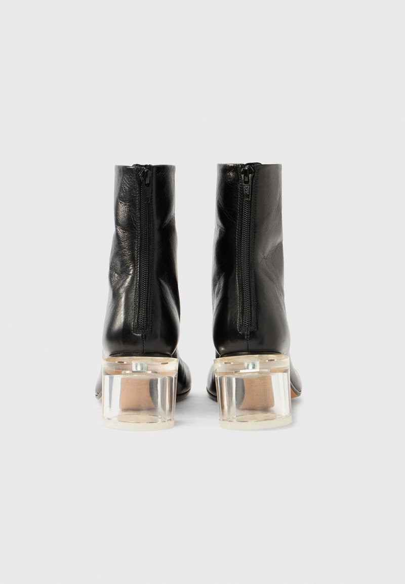 Sorte læderankelstøvler med en glat tekstur, side lynlåse og klare blokhæl. Designet har en minimalistisk, slank silhuet.