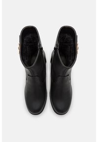 Par de botas de cuero negro para invierno con forro de piel, vistas desde arriba sobre un fondo blanco liso.