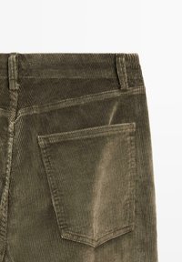 Olivengrønne corduroypants med vertikal ribbet tekstur, der har en baglomme og syede detaljer langs taljen og siderne.