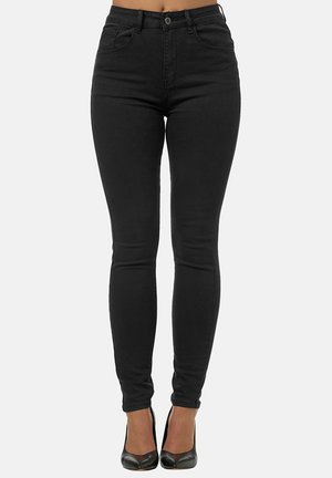 Jean skinny noirs en denim, à taille haute, avec cinq poches et une texture lisse, associés à des escarpins noirs.