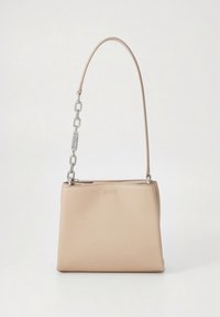 Bolso sintético beige con textura lisa, que presenta una correa larga y detalles de cadena metálica. En la parte delantera está grabado "HUGO". Cierre de cremallera en la parte superior.