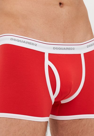 Boxer-briefs en coton rouge avec une taille accentuée blanche portant le logo "DSQUARED2" en gris. Texture lisse, design ajusté et braguette fonctionnelle.