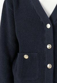 Navy knitted cardigan with ribbed texture, V-neck, two front pockets, and gold-tone button accents.