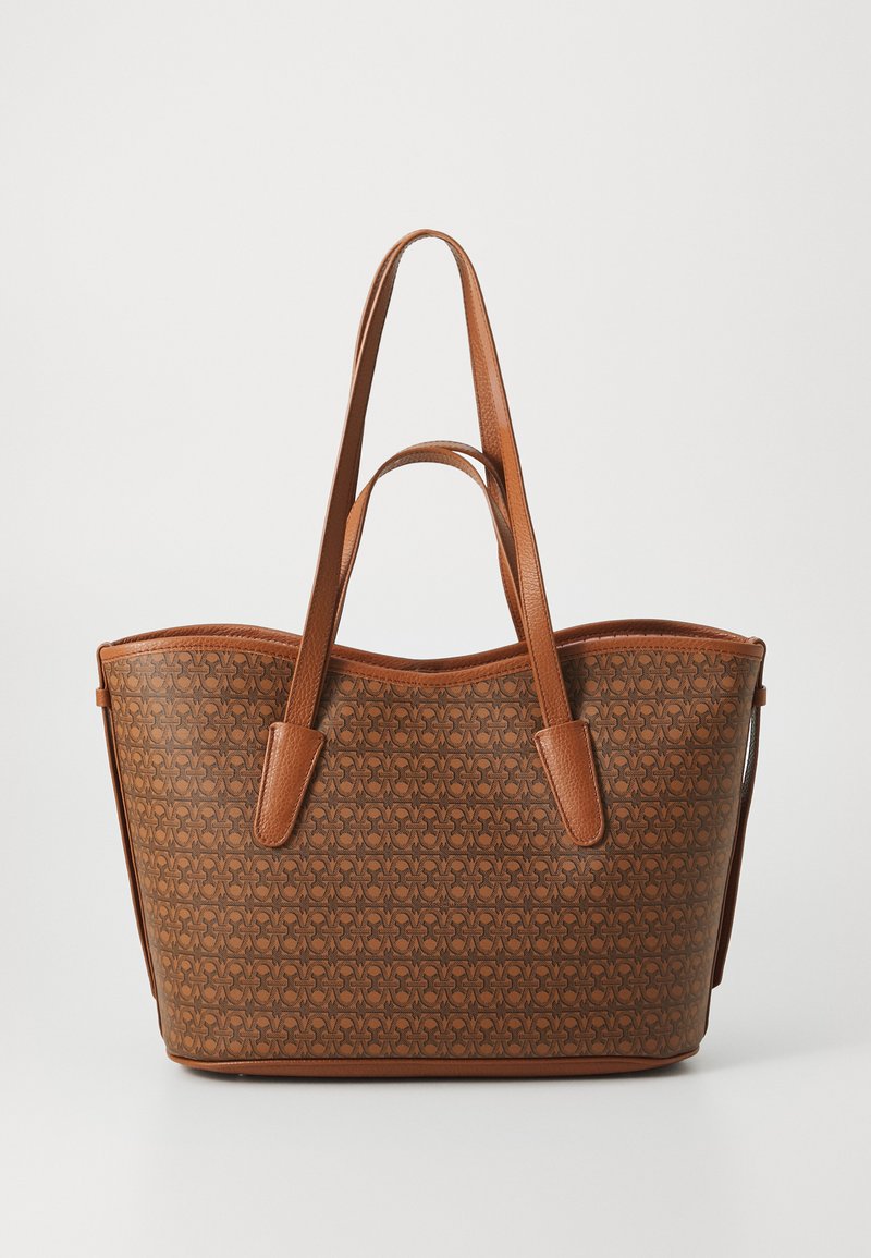 Sac fourre-tout marron en matériau synthétique texturé, doté d'un motif répété, de deux poignées à plat, et d'une large ouverture sur le dessus.