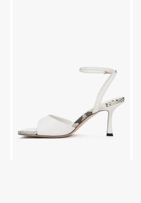 Witte hoge hakken sandalen met open teen, enkelbandje en een textuur van slangenprintaccent op de hak. Gladde leren bovenkant en zwarte hakpunt.