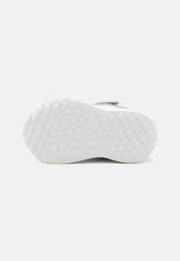 Sloj nike tenisice s teksturiranom bijelom gumom, koji sadrži valoviti uzorak okruglih i ovalnih udubljenja za bolje prianjanje.