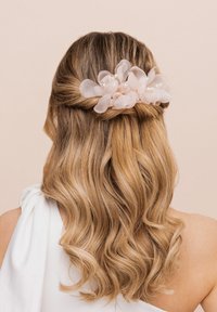 Accessorio per capelli con un gruppo di morbide fiori in tessuto rosa e accenti di perle, posizionato su capelli biondi lunghi e mossi.