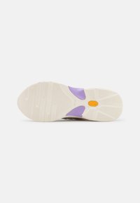 Suola di scarpa in gomma color crema e viola, con motivi testurizzati e scanalature per la trazione, accompagnata da un logo visibile impresso al centro.
