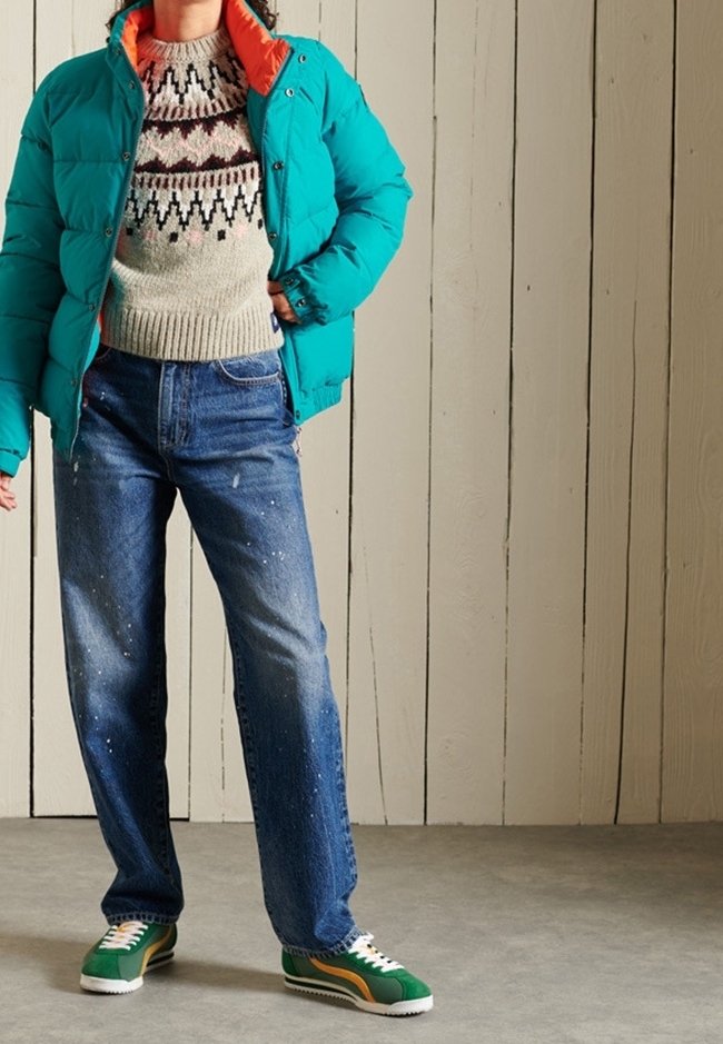 Turkoosi puhvitakki oranssilla yksityiskohdilla, harmaa kuvioitunut villapaita, siniset farkut ja vihreät tennarit keltaisilla ja valkoisilla raidoilla.