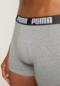Graue Baumwoll-Boxershorts mit einem schwarzen elastischen Bund, der mit weißen "PUMA"-Markierungen versehen ist, und einem glatten Stoff sowie körperbetontem Design.