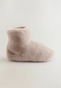Kerge beeži värvi fleece-jalanõud. Pehme, siledat tekstuuri, ümara varbaga ja keskmise profiiliga disain, sobivad siseseks kandmiseks.