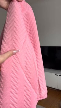 Indumento in tessuto testurizzato rosa con un motivo a spina di pesce, caratterizzato da una superficie liscia e bordi rifiniti. Il design appare morbido e leggero.