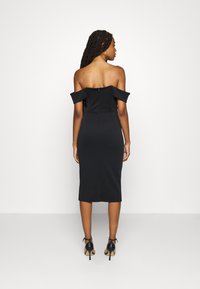 Robes noires cintrées à épaules dénudées avec un ourlet mi-long. Tissu doux et fermeture éclair dissimulée dans le dos. Associée à des chaussures à talons hauts noires.