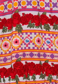 Tkanina w wielu kolorach z czerwonymi różami, wzorami geometrycznymi i tekstem z logo. Projekt zawiera paski w odcieniach pomarańczowym, purpurowym i różowym.