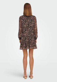 Robe fleurie transparente présentant un motif cachemire noir et rose, manches longues et ourlet à volants en étages. Tissu lisse avec une coupe décontractée.