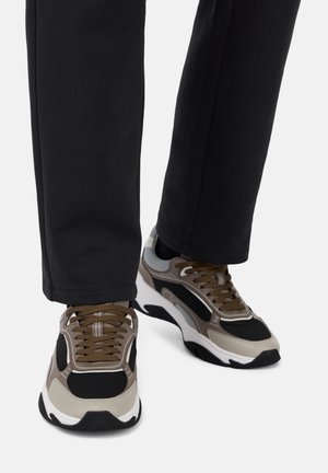 Zapatillas chunky en beige, gris y negro. Materiales de malla y sintéticos con puntera redonda, acentos en contraste y cordones marrones.