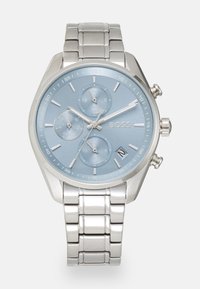 Relógio de metal prateado com um mostrador azul claro, três submostradores, marcadores de horas prateados e uma bracelete de liga de aço inoxidável. Apresenta três botões de pressão.